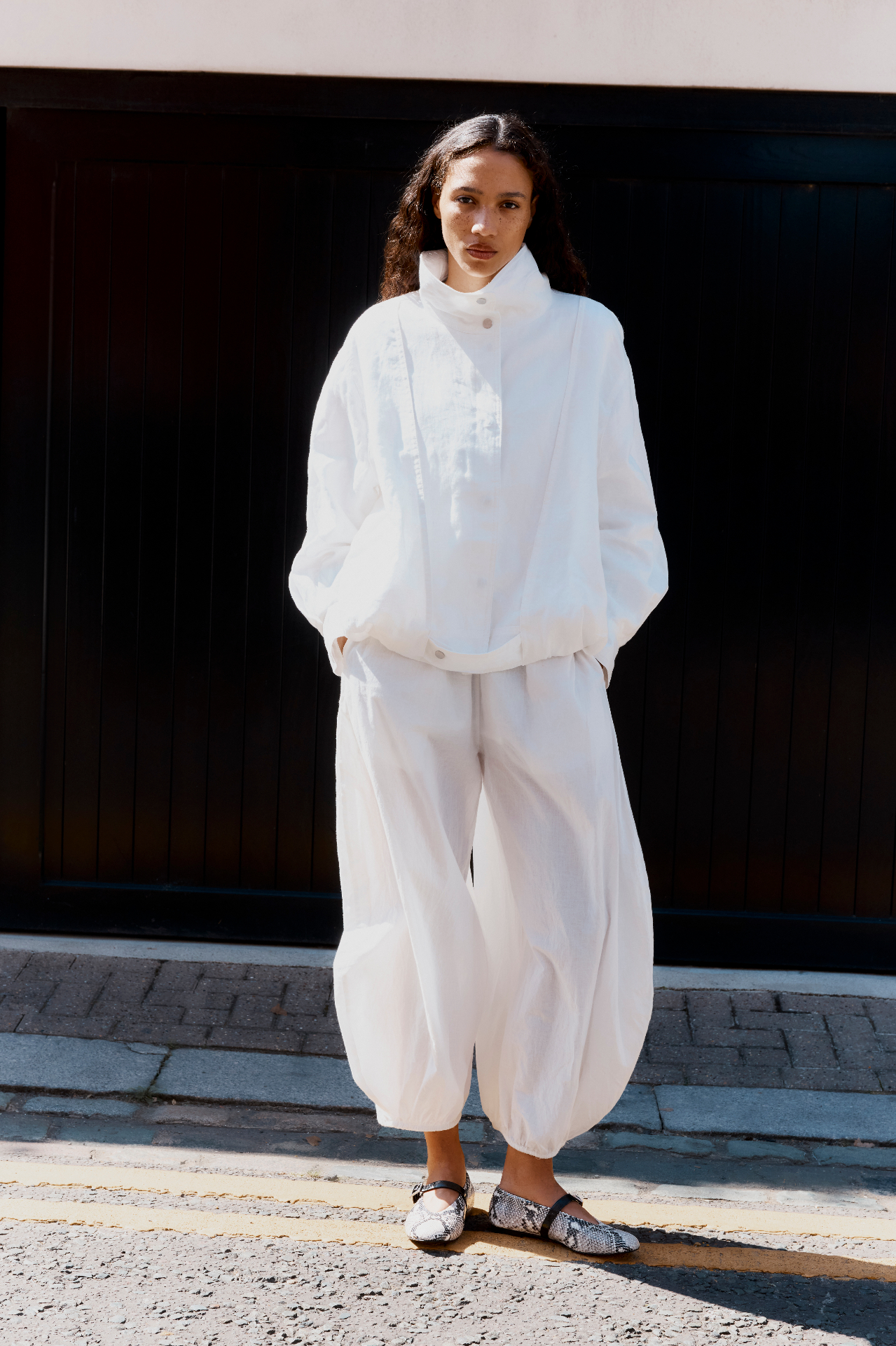 THE L—INE — model in white outfit with snake mary-jane flats